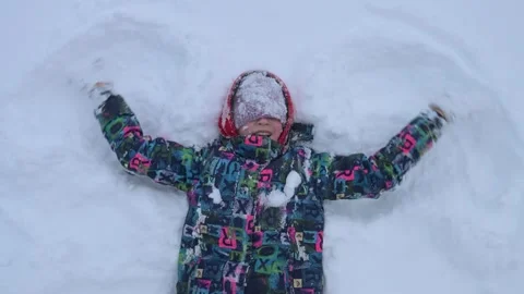 Child makes an snow angel while lying in the snow. Stock Footage 297865346