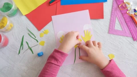 Child making card with Easter funny eggs and flowers from colorful paper. Stock Footage 172340383
