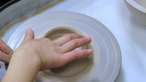 Child making ceramic vase on rotating pottery wheel at workshop. Video stock 324419673