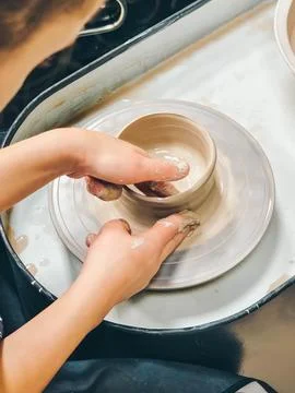 Child making ceramic vase on rotating pottery wheel at workshop. Creativity. Stock Photos