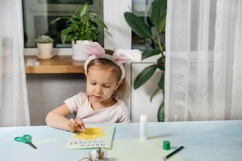 Child making Easter egg gift card with a bunny from paper Stock Photos