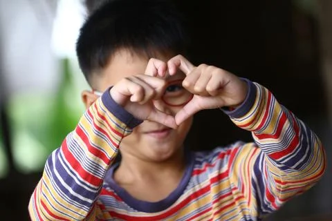 Child Making Heart Shape with Hands in Colorful Shirt Stock Photos