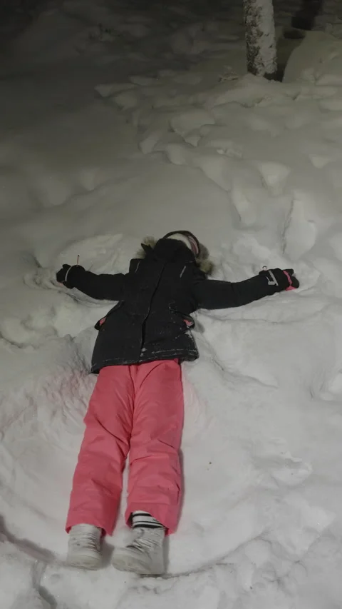 Child making a snow angel at night in winter Stock Footage 346192247