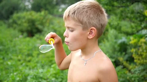 Child making soap bubbles outdoors 库存影片 65375699