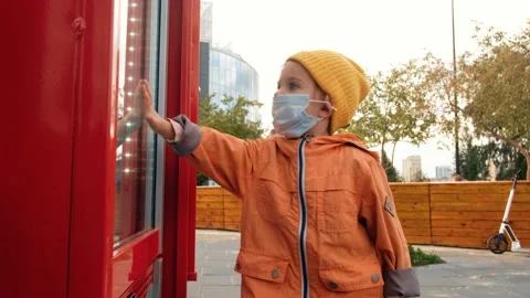 Child in mask touching window Stock Footage 137687556