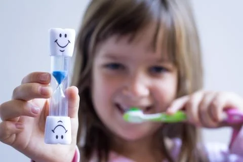 Child measures time while brushes her teeth. Healthy habits, dental care concept Stock-Fotos