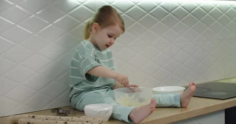 Child mixes batter with spoon at kitchen counter Видео 333522877