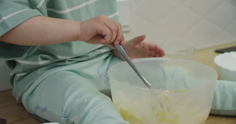 Child mixes batter with spoon at kitchen counter Stock-Footage 333523077