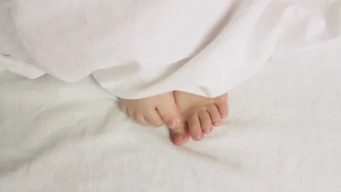 The child moves his legs under the covers. Stock Footage 207521179