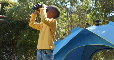 Child is noticing drone overhead, raising binoculars and following drone in sky Stock Footage 344331098