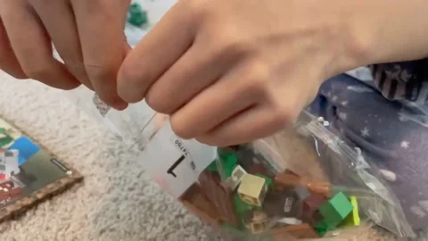 Child opening bag number 1 of a brand new LEGO Building set. Close up of Stock Footage 145794635