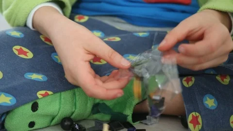 Child opening a plastic bag with interlocking plastic bricks toy Stock Footage 123492443