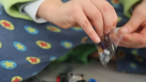 Child opening a plastic bag with interlocking plastic bricks toy Stock Footage 123492546