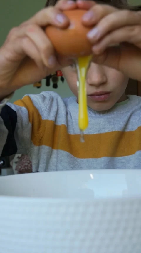 Child opening a raw egg to make a cake Stock Footage 250971584