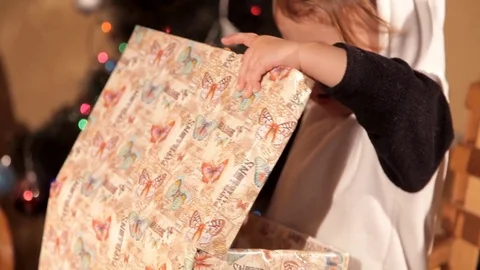 Child opens a New Year's gift near a Christmas tree Stock Footage 82508860