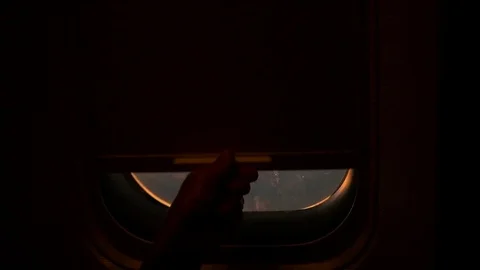 The child opens the shutter of the window on the airplane to see the sunset 库存影片 74506216