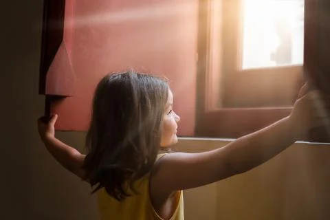 The child opens the window shutters Stock Photos
