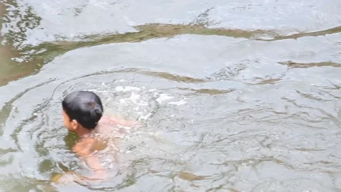 Child or kid playing with water or swimming on a local pond at Madhyamgram. Stock Footage 171761653