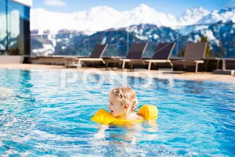 Child in outdoor swimming pool of alpine resort Stock Photos