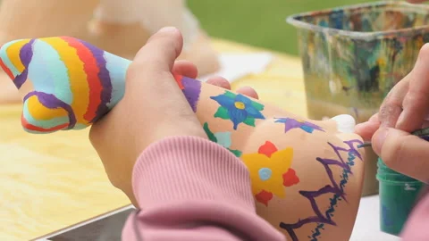 Child painting brushes on the clay figure outdoors Stock Footage 94131953