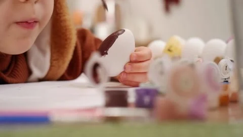 Child painting easter eggs on table Stock Footage 303351019