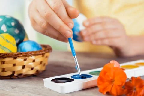 Child paints Easter egg in blue color Stock Photos