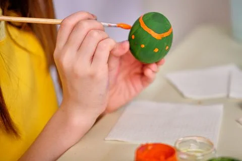 A child paints Easter eggs with paints. Hands paint an Easter wooden egg with Stock Photos