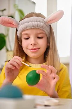 A child paints Easter eggs with paints. Portrait of caucasian girl, child 9-10 Stock Photos