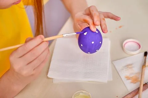 A child paints Easter eggs with paints. Hands paint an Easter wooden egg with Stock Photos