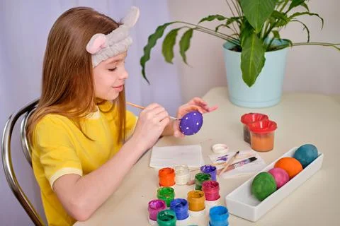 A child paints Easter eggs with paints. Portrait of caucasian girl, child 9-10 Stock Photos