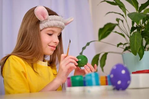 A child paints Easter eggs with paints. Portrait of caucasian girl, child 9-10 Stock Photos