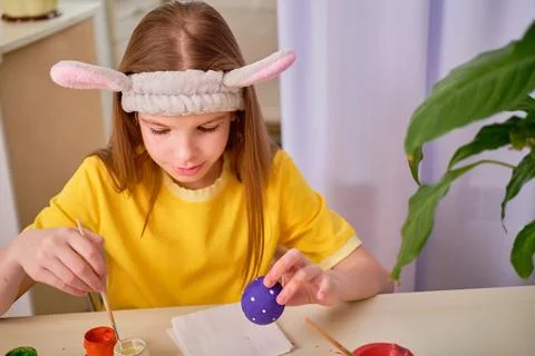 A child paints Easter eggs with paints. Portrait of caucasian girl, child 9-10 Stock Photos