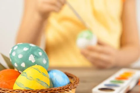 Child paints egg for Easter, focus on eggs Stock Photos