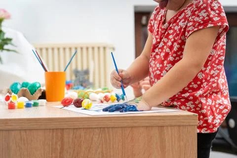 Child paints her hand at an Easter activity on a bright table in a cozy house Stockfoto's