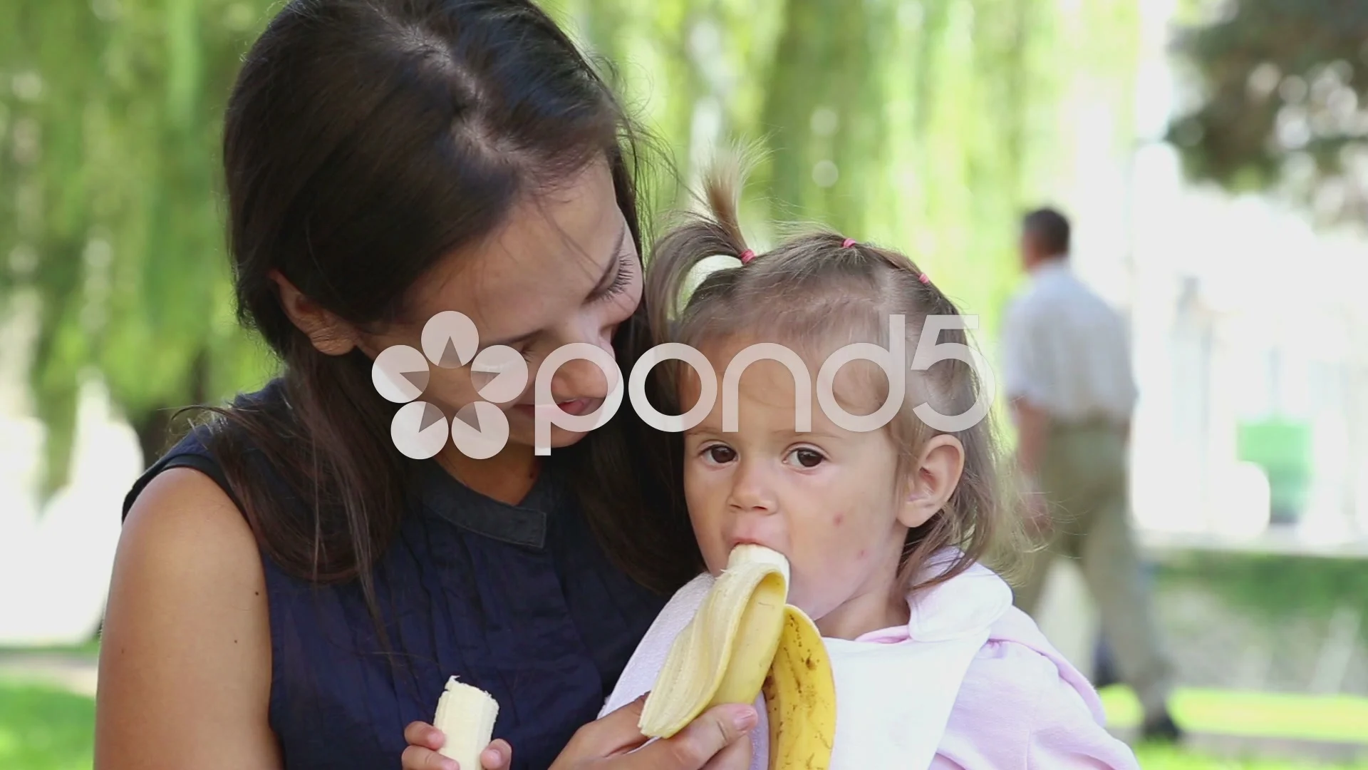 The child in the park next to my mom eats a banana.