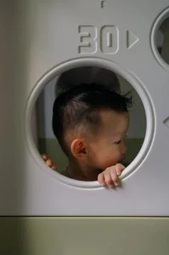 Child peeking through play structure Foto stock