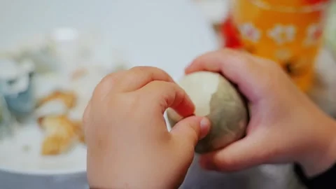 Child Peeling Naturally Dyed Easter Egg During Traditional Family Celebration Stock Footage 338346542