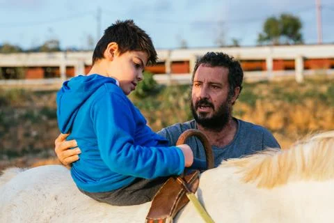 Child performing upper trunk exercises during equine therapy Stock Photos