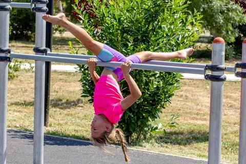 Child performing an upside-down split on a horizontal bar Stock Photos