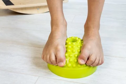 The child performs exercises on the balancer from the valgus of the foot. The Stock Photos