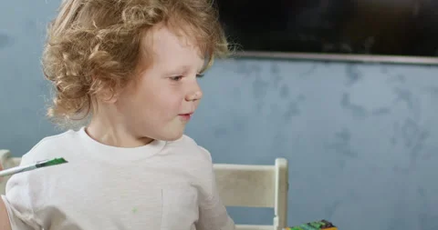 Child pets cat holding paintbrush in hand during lesson Video stock 277562953