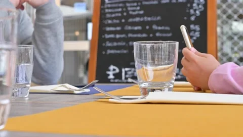 A child with a phone at a cafe, restaurant table. Stock Footage 131697053