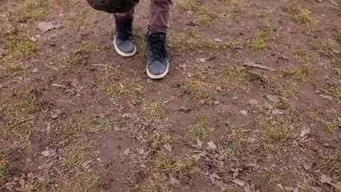 Child picking up trash in park with parent holding garbage bag, environmental Stock Footage 334151000