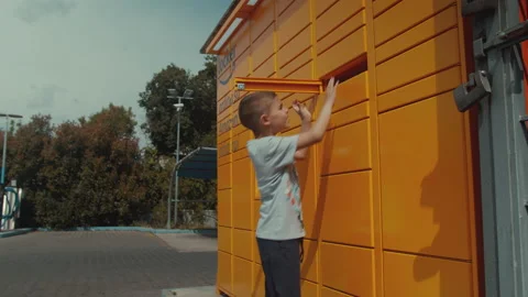 Child picks up the parcel from the amazon locker vending machine Stock Footage 131248552