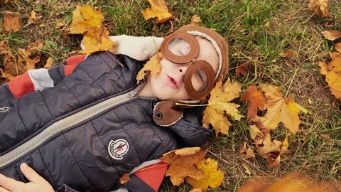 Child pilot aviator lay on a fallen leaves in autumn forest. Stock Footage 229101256