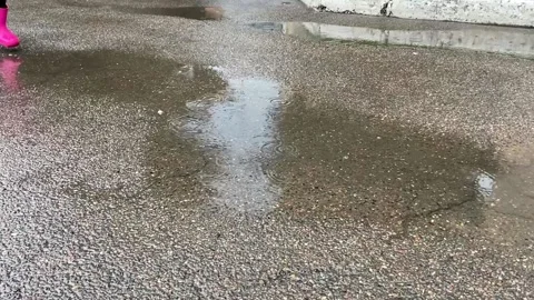 A child in pink boots runs in a puddle Stock Footage 166314142