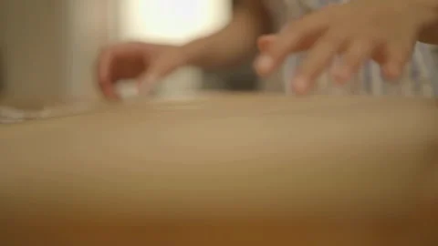 Child placing parchment paper flat on work surface Видео 336374547