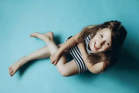 Child on plain blue background looking at camera sitting Stock Photos