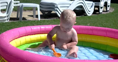 Child Play and Having Fun in Inflatable Pool on Green Lawn in a Sunny Day Stock-Footage 65781034