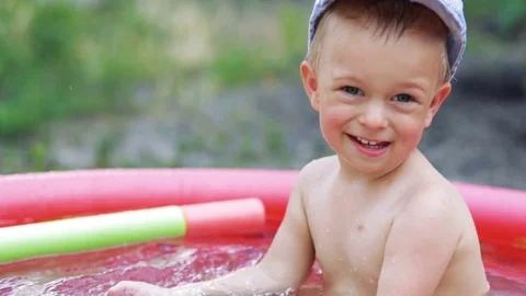 Child play and having fun in inflatable rubber pool of green lawn on a sunny day Stock Footage 77804236